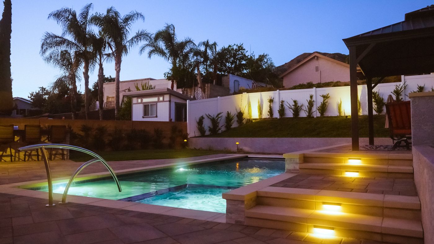 Landscape lighting illuminating a backyard patio at dusk